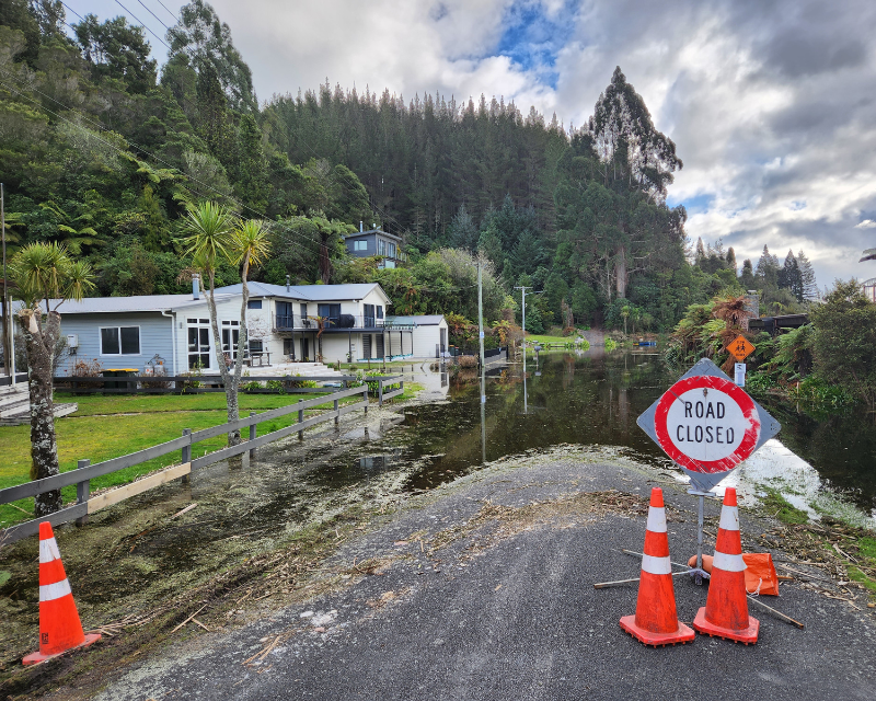 Road closed traffic sign with traffic cones in front of a flooded road